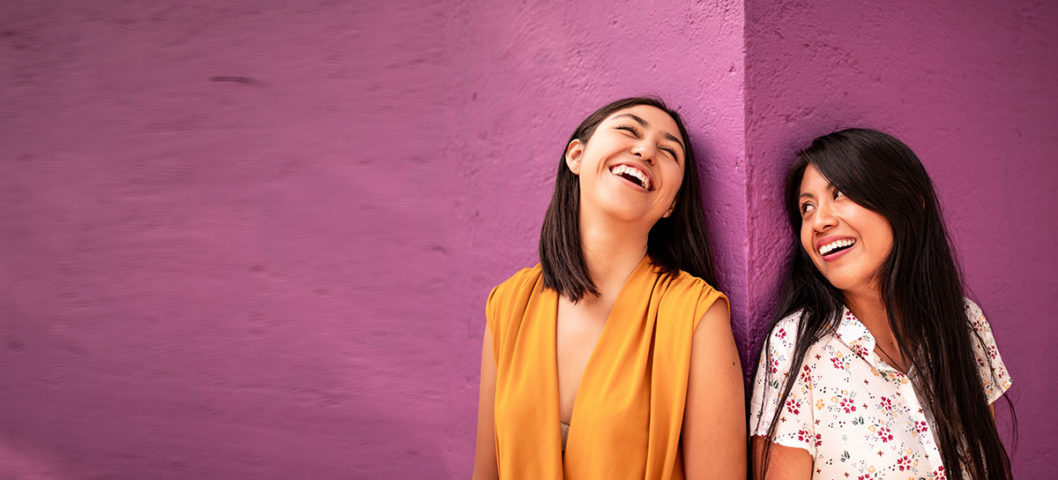 Two best friends leaning against wall enjoying time together