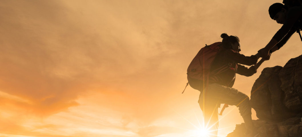help each other silhouette in mountains with sunlight.