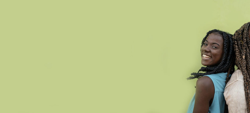 Two siblings taking a picture together to celebrate sibling day on a green background