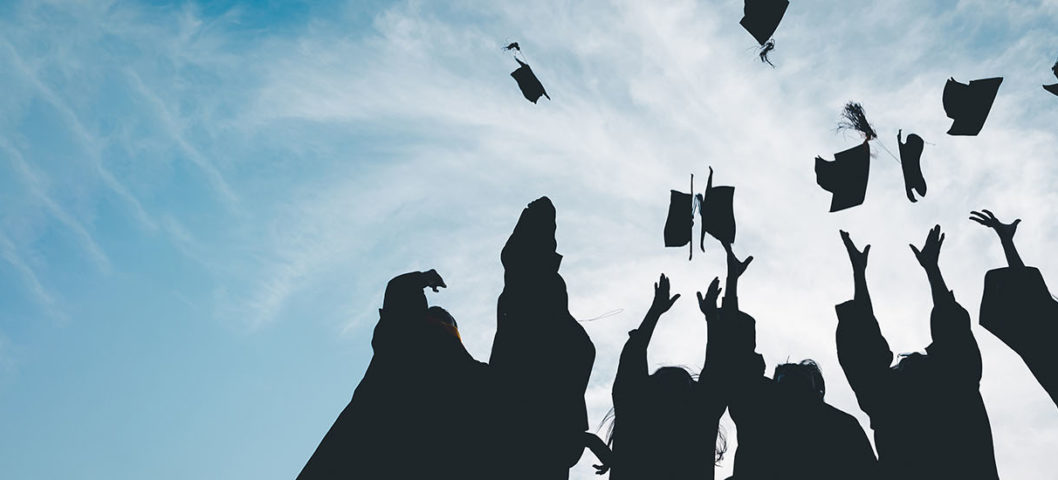 Group-of-high-school-graduate-students-throwing-their-caps-in-the-air-at-graduation