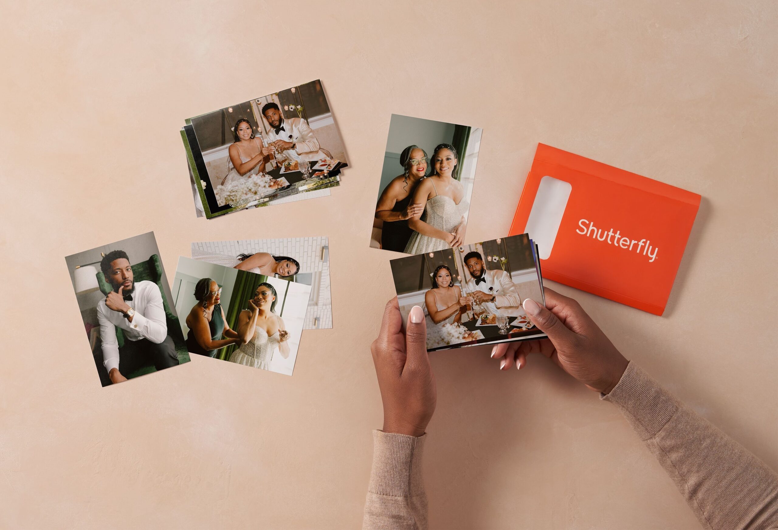 person holding photo prints and a shutterfly envelope