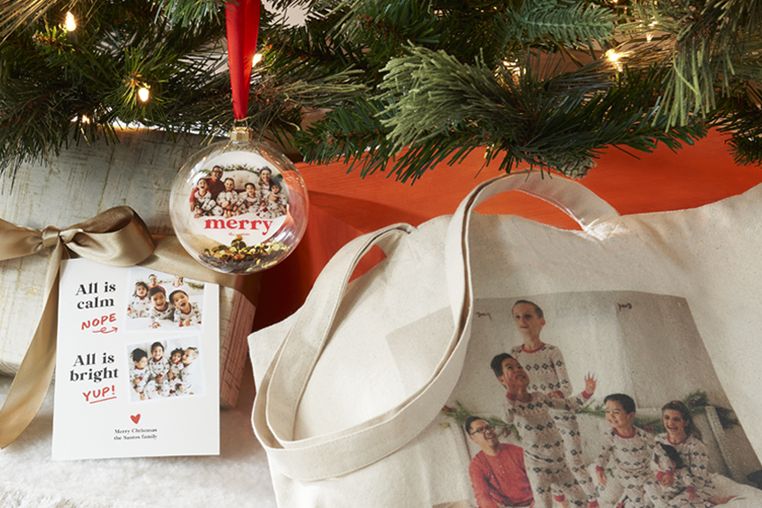 christmas card, photo ornament, and tote bag under a christmas tree