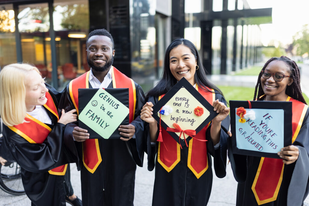 Graduation. Students after graduation ceremony holding their mortarboard with creative messages