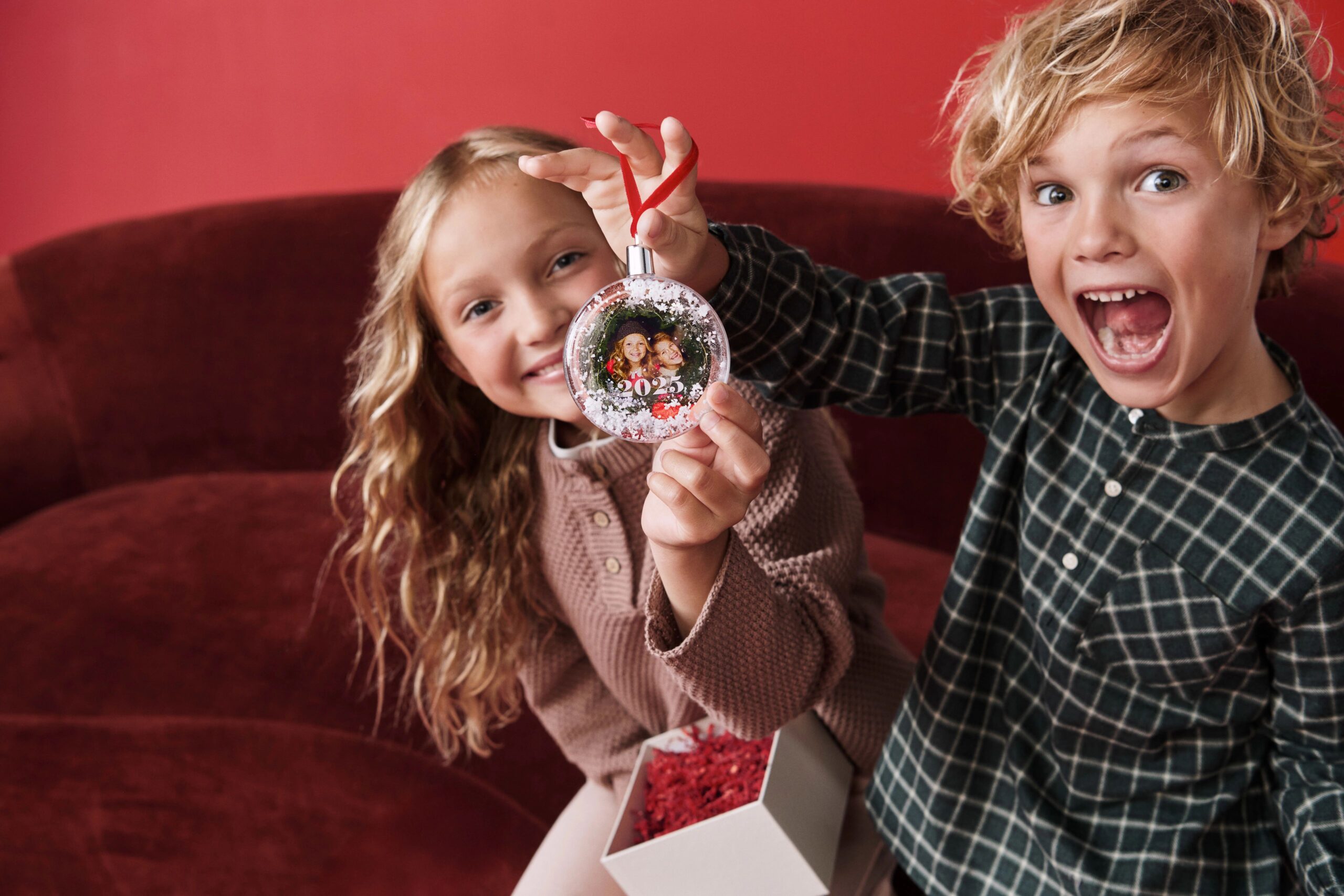 two kids holding a snow globe ornament