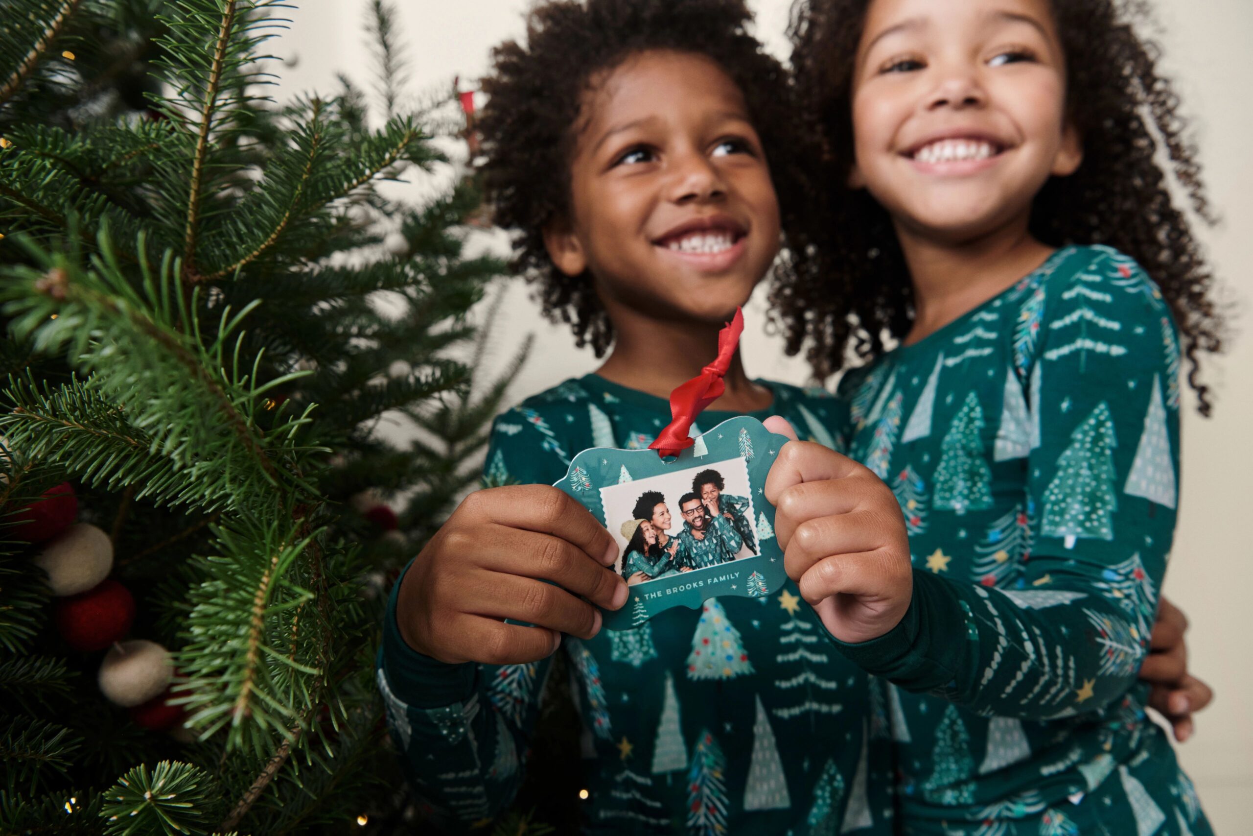 two kids holding a metal christmas ornament